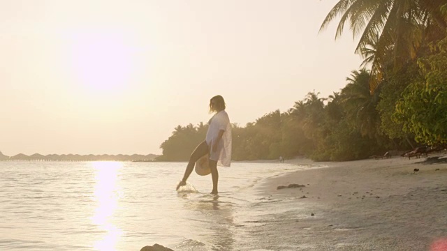 女士涉水在热带海洋冲浪在宁静的日落海滩，马尔代夫视频素材