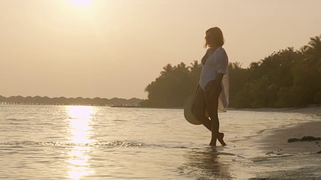 女士涉水在热带海洋冲浪在宁静的日落海滩，马尔代夫视频素材