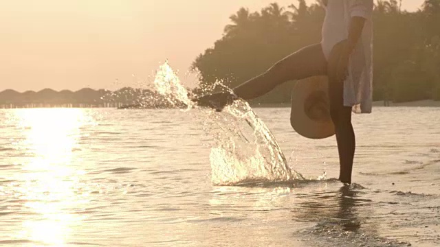 女士涉水，在宁静，热带海洋冲浪日落，马尔代夫视频素材