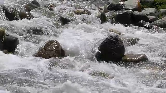 湍急的河流溅起水花，在山谷中的岩石上流动，动作缓慢视频素材