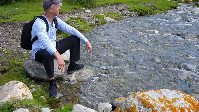 游客坐在石头上，以山河流水为背景视频素材