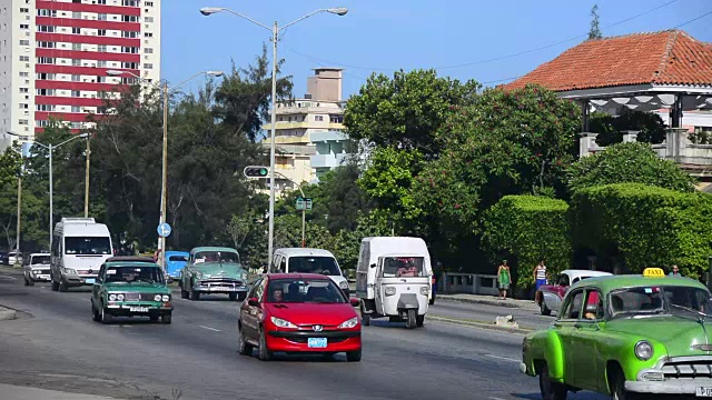 古巴哈瓦那:老爷车开在城市大道上的新车中间视频素材