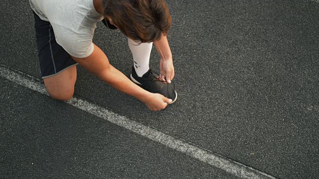 混合赛跑运动员系鞋带，准备在体育场赛跑视频素材