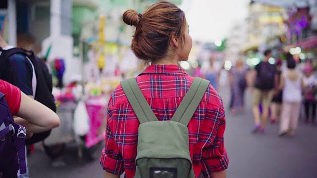 旅行家背包亚洲女人旅行在考山路在曼谷，泰国。快乐的年轻女性在惊人的地标假日旅行，享受她的旅程在传统城市。视频素材