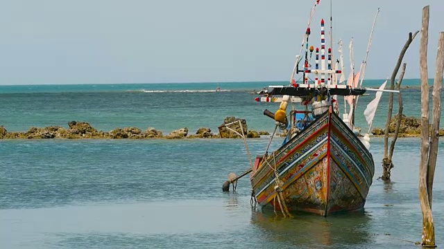 热带海洋海滩景观用传统的木制小渔船系泊。泰国苏梅岛亚洲贫穷的穆斯林渔村附近的海景。船上有旗子和灯。视频素材