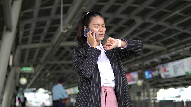 亚洲女商人在等待火车到达时打电话。视频素材