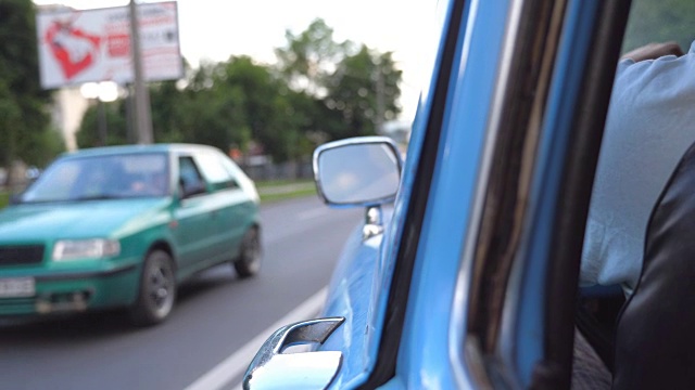 从后视图看夏天在城市街道上行驶的老式汽车。在市中心的柏油路上，一个面目全的男人开着一辆蓝色的老爷车。后视图近景慢动作视频素材