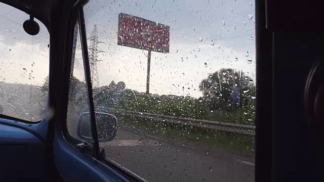 透过侧窗的旧复古汽车，而移动在雨天。在乡下开车时，雨点落在一辆老式汽车的玻璃上。特写慢动作视频素材