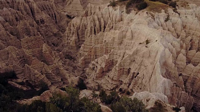 无人机鸟瞰图倾斜下来的史前Badlands峡谷斑点与植被在白天视频素材