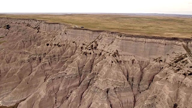 无人机在Badlands国家公园的山丘和灌木之间的冒险乡村公路的鸟瞰图视频素材