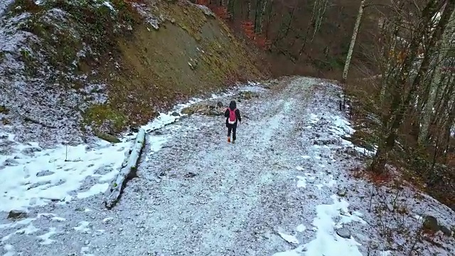 一个年轻人走在雪山路上在一个冬天的一天视频素材