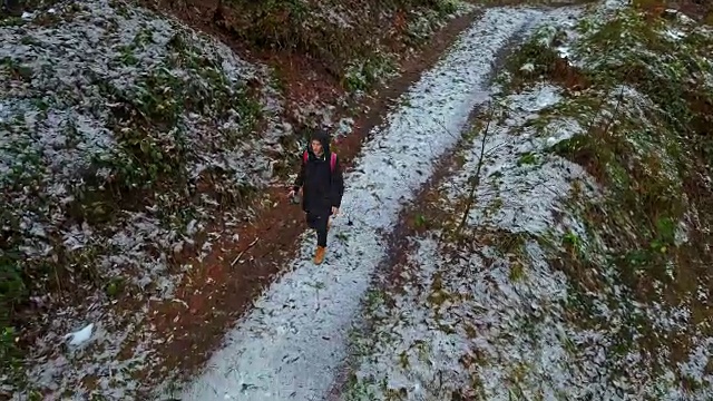 一个年轻人走在雪山路上在一个冬天的一天视频素材