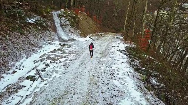 一个年轻人走在雪山路上在一个冬天的一天视频素材