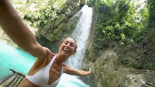 一名年轻女子在菲律宾宿务岛与美丽的瀑布自拍。人们旅游自然自拍的概念。一个人只喜欢户外和一个宁静的环境-慢动作视频视频素材