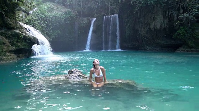 在菲律宾的宿务岛，一个年轻的女人凝视着美丽的瀑布。人们旅行热爱自然的理念。一个人只喜欢在一个宁静的环境里享受户外的宁静视频素材