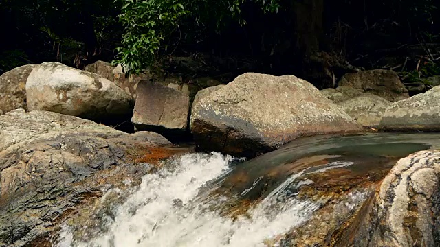 神奇的热带雨林和河流与岩石的风景。野生植被，深热带森林。丛林里的树木和湍急的岩石溪流。蒸汽和石头瀑布流过异国的树林。视频素材