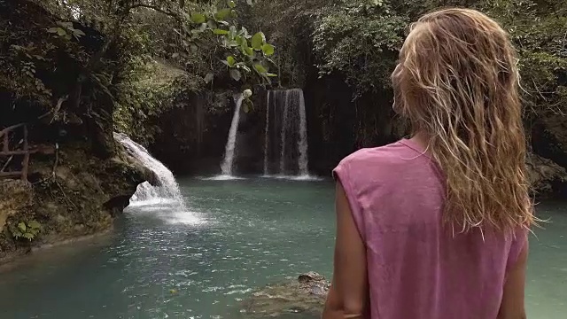 在菲律宾的宿务岛，一个年轻的女人凝视着美丽的瀑布。人们旅行热爱自然的理念。一个人只喜欢在一个宁静的环境里享受户外的宁静视频素材