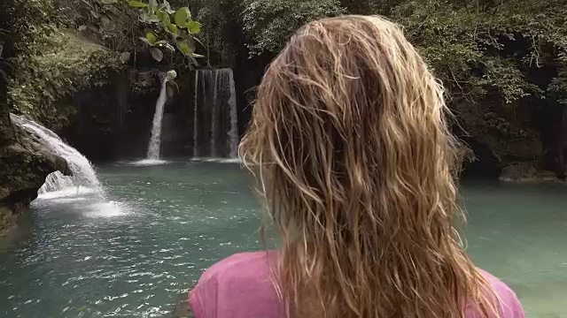 在菲律宾的宿务岛，一个年轻的女人凝视着美丽的瀑布。人们旅行热爱自然的理念。一个人只喜欢在一个宁静的环境里享受户外的宁静视频素材