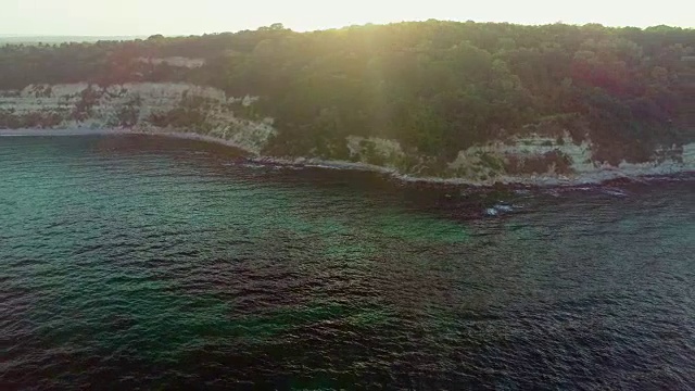 在日出时，无人机拍摄的岩石海岸线与汹涌的海浪视频素材