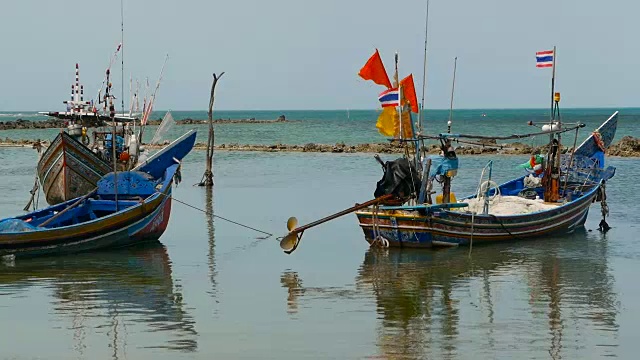 热带海洋海滩景观用传统的木制小渔船系泊。泰国苏梅岛亚洲贫穷的穆斯林渔村附近的海景。船上有旗子和灯。视频素材