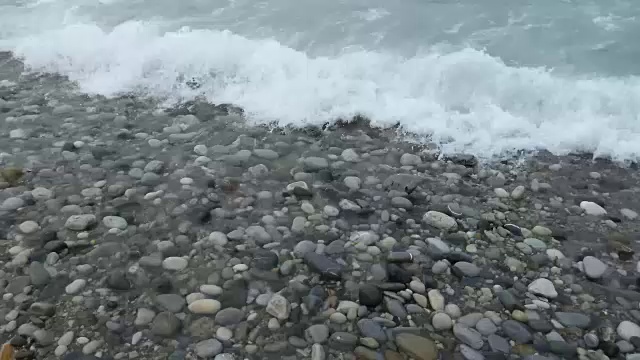 纯净的水波在五颜六色的抛光石头和鹅卵石上游动视频素材