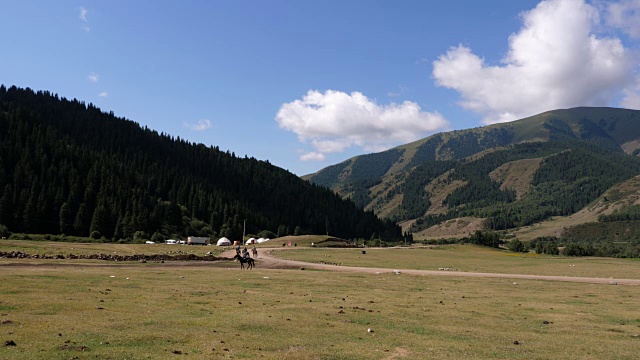 骑马者在田野与天山山脉在吉尔吉斯斯坦视频素材