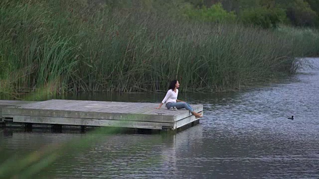 年轻的亚洲女子在湖边放松视频素材