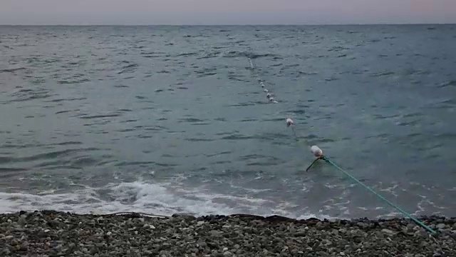 海边的夏日黄昏。一根长绳子和一些漂浮物进入水中视频素材