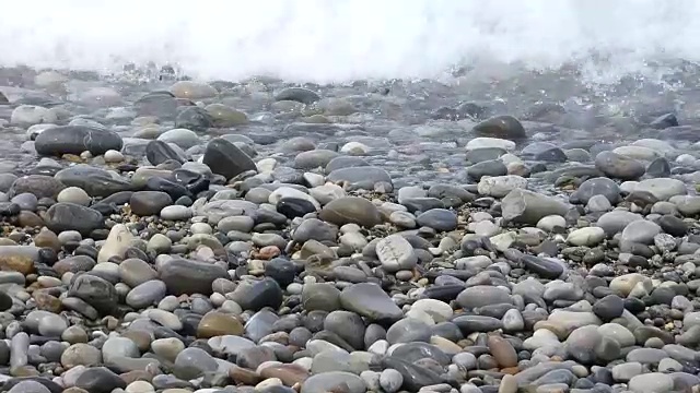 纯净的水波在五颜六色的抛光石头上移动视频素材