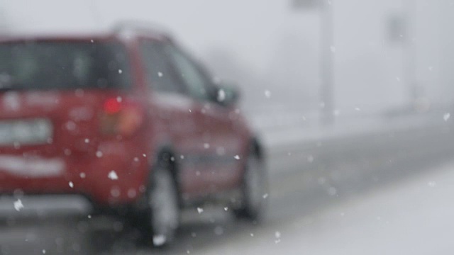 慢镜头:一辆橙色的汽车在一个下雪天小心地行驶在空旷的高速公路上。视频素材