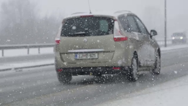 慢镜头:在一场强烈的暴风雪中，交通行驶在积雪的公路上。视频素材