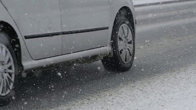 特写:在一场危险的暴风雪中，车辆沿着光滑的道路行驶。视频素材