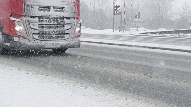 慢镜头:一辆载着货物的卡车在下雪天沿着光滑的道路行驶。视频素材