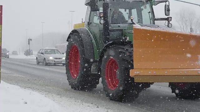 慢镜头:拖拉机和汽车在雪道上行驶。视频素材