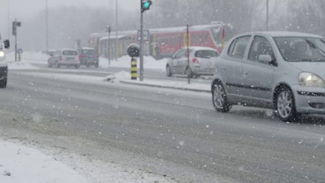 慢动作:在危险的暴风雪中，城市车辆在光滑的道路上行驶。视频素材