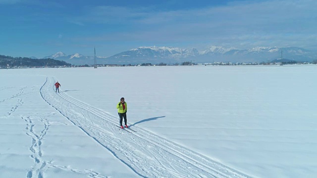 图片:两个女游客在一个阳光明媚的日子里进行越野滑雪。视频素材