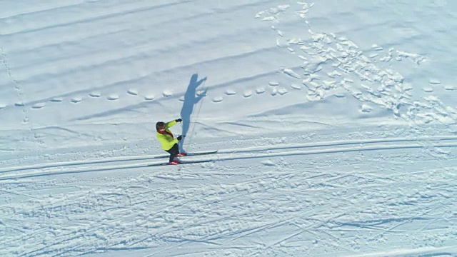 航拍:活跃的女子沿着大平原上的雪道越野滑雪。视频素材