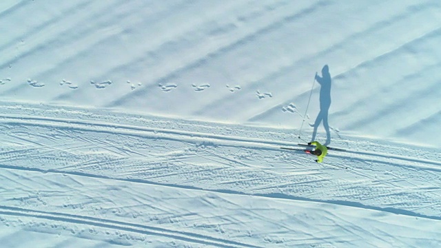 空中摄影:在阳光明媚的日子里，飞过在狭窄小道上滑雪的精力充沛的女人。视频素材