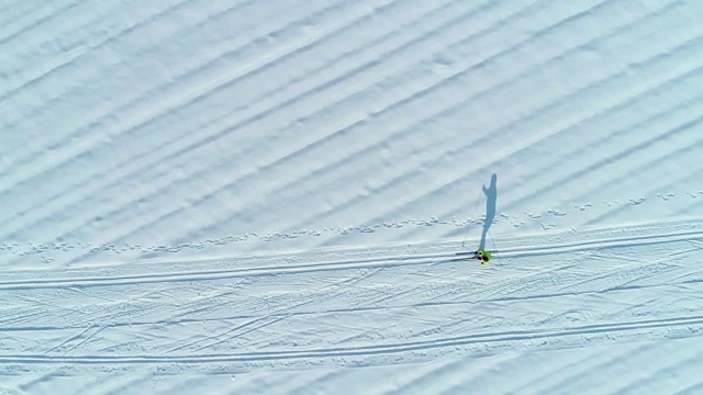 航拍:女子越野滑雪和她在雪地里的影子的酷镜头。视频素材