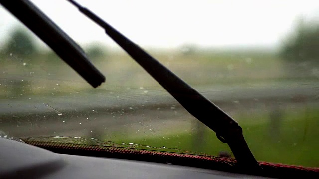 特写，雨，汽车雨刷的工作，挡风玻璃雨刷从汽车内部，汽车雨刷清洁玻璃上的雨滴视频素材