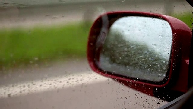 特写，在开车时，车的侧窗上有水滴。在强风中，水滴不是顺着玻璃流下，而是向上流动。透过车窗可以看到侧后视镜视频素材