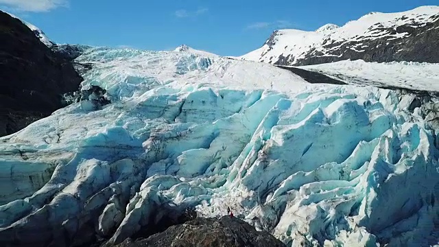 鸟瞰冰川附近岩石上的徒步旅行者视频素材