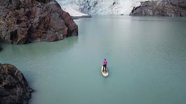 鸟瞰图妇女站在冰川附近划桨视频素材