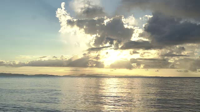 乌云遮住了太阳，在天空下的海滩上有小波浪。视频素材