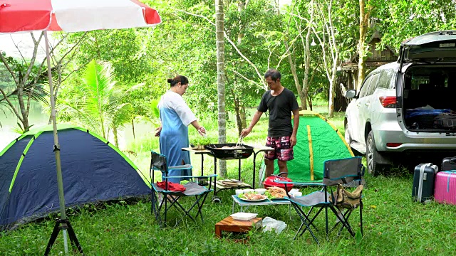 一家人乘车旅行，在假期露营，在帐篷里休息，在森林里吃烤海鲜。视频素材