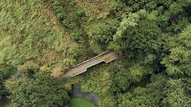 俯视图，旋转移动。在英国乡村杂草丛生的池塘里，无人机在古老的小砂岩桥上旋转。视频素材