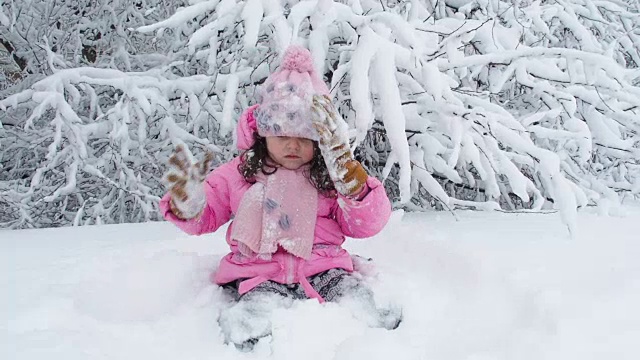 一个孩子坐在雪地里。视频素材