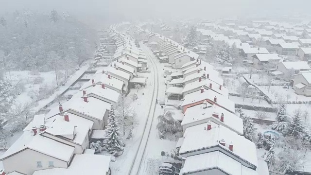 航拍图:在暴风雪中，一个无法辨认的成年人正在铲自家车道上的雪。视频素材