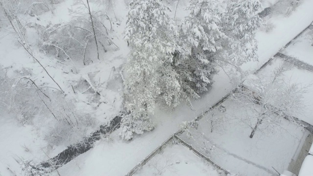 鸟瞰图:在积雪的郊区，飞过流过后院的河流。视频素材