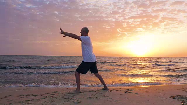 一名男子在海滩和日落景观上练习武术太极拳视频素材